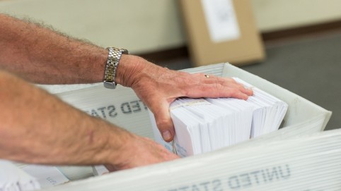 A man's hand in a tray of mail