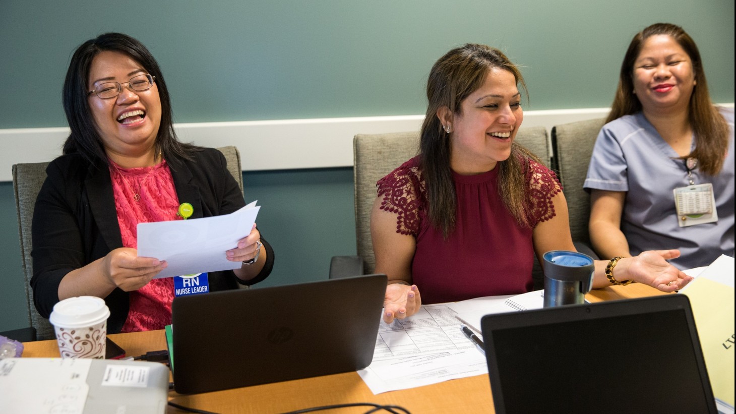 three women in a meeting, laughing together