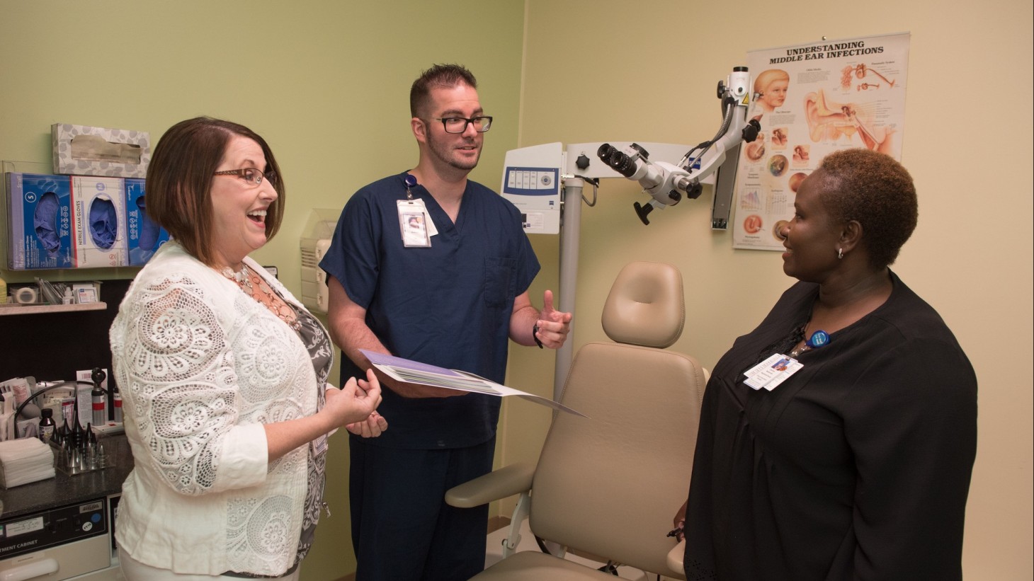 three people talking together in an audiology exam room