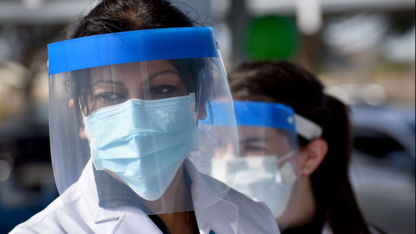 Two women in face shields and masks working at the drive-up hypertension clinic