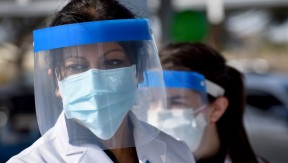 Two women in face shields and masks working at the drive-up hypertension clinic